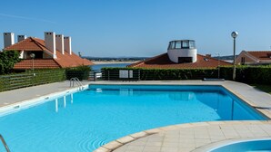 En swimmingpool med udsigt til stranden og en bygning med rødt tag.