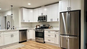 A modern kitchen with white cabinets, stainless steel appliances, and a wooden floor. - Great central location! Cozy 3-Bedroom, 2-Bath Retreat on Acreage-Quiet Country (Atascadero)