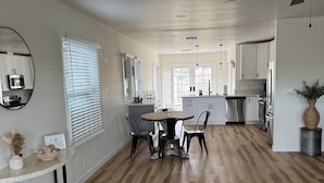 A spacious kitchen with white cabinets, a central island, and a dining area with a round table and chairs. - Great central location! Cozy 3-Bedroom, 2-Bath Retreat on Acreage-Quiet Country (Atascadero)