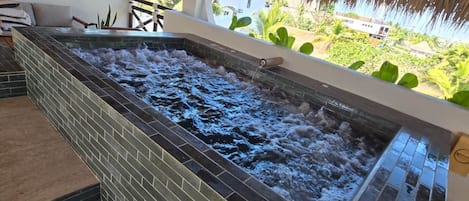 A spa area with a hot tub, tiled flooring, and a thatched roof.