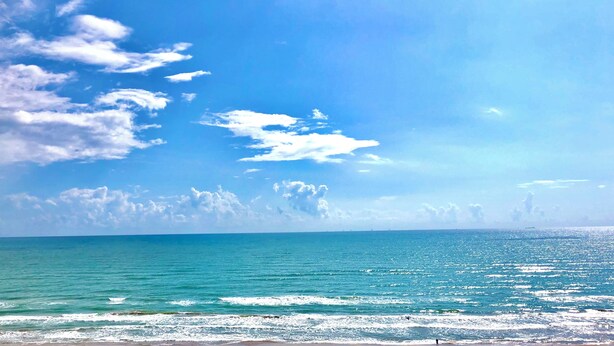 Een strand met helderblauw water en een strakblauwe lucht.