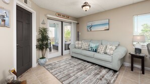 Een woonkamer met een lichtblauwe bank, een potplant, een lijst met foto en een bord waarop 'South Padre Island' staat.