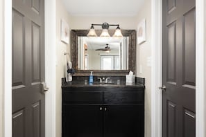 Une salle de bain avec un meuble-lavabo en bois foncé, un grand miroir et un ventilateur de plafond.