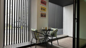 Ein modernes Zimmer mit Glastrennwand, einem kleinen Tisch mit Stühlen und Kunstwerken an der Wand.