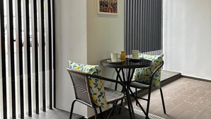 Ein zeitgemäßer Essbereich mit einem runden Tisch und Stühlen, einer Wand mit dekorativen Bildern und einem vertikalen Rollo-System.