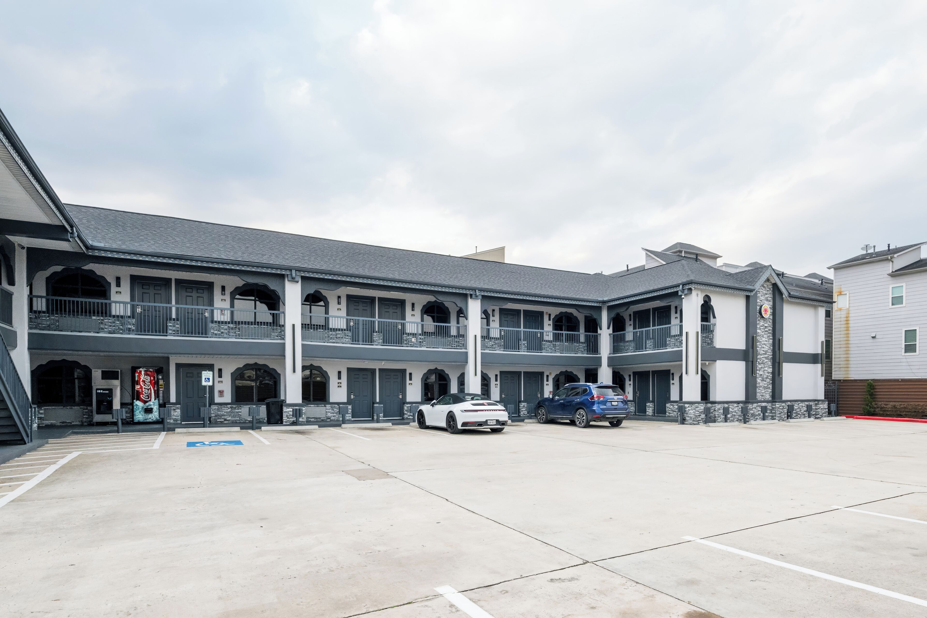 A multi-story building with a central courtyard, parking spaces, and a blue handicap-accessible sign.