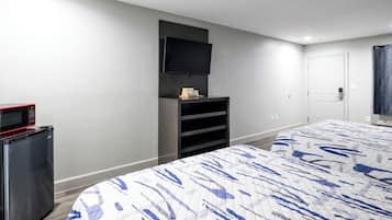 A hotel room with a bed, a TV mounted on the wall, a mini-fridge, and a door with a handle.