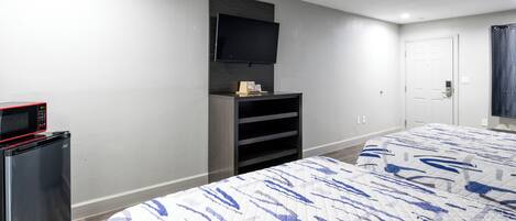 A hotel room with a bed, a TV mounted on the wall, a mini-fridge, and a door with a handle.