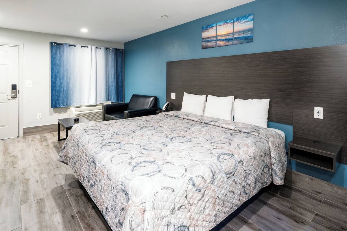 A bedroom with a large bed, a desk, and a chair.