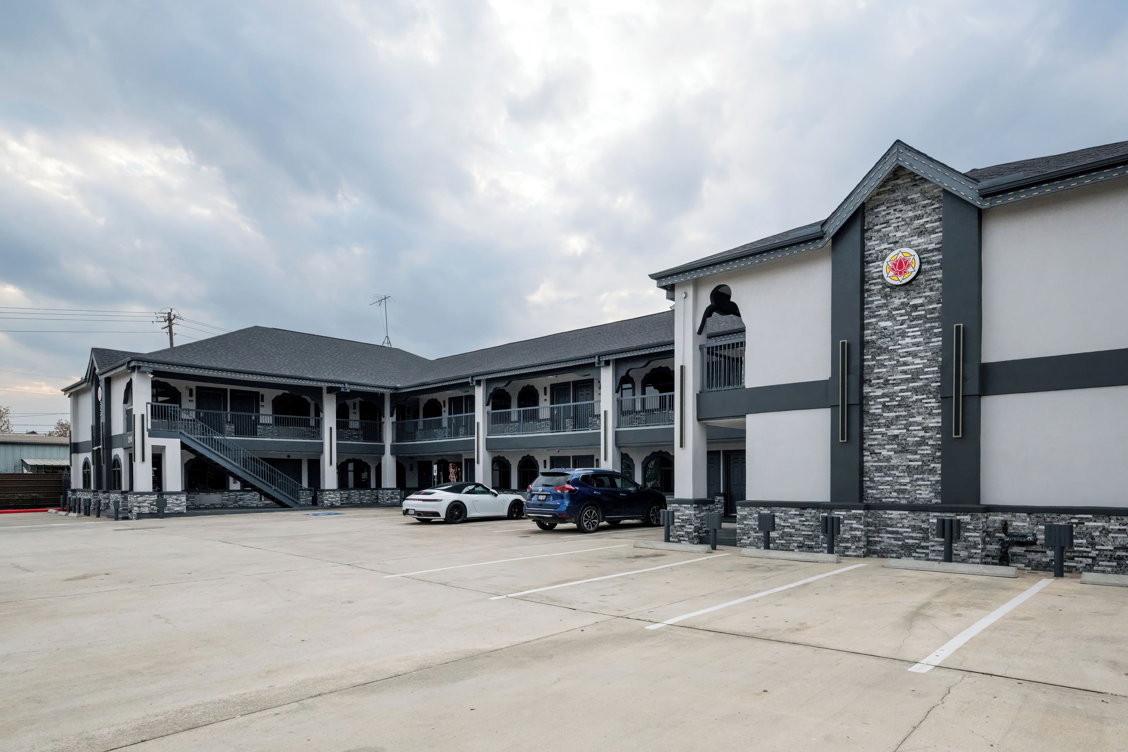 A multi-story building with a parking lot, featuring a prominent logo on the facade.