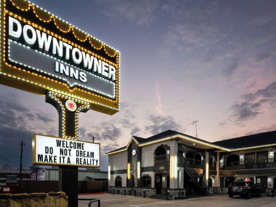 A hotel sign with "DOWNTOWN INNS" and a welcoming message.