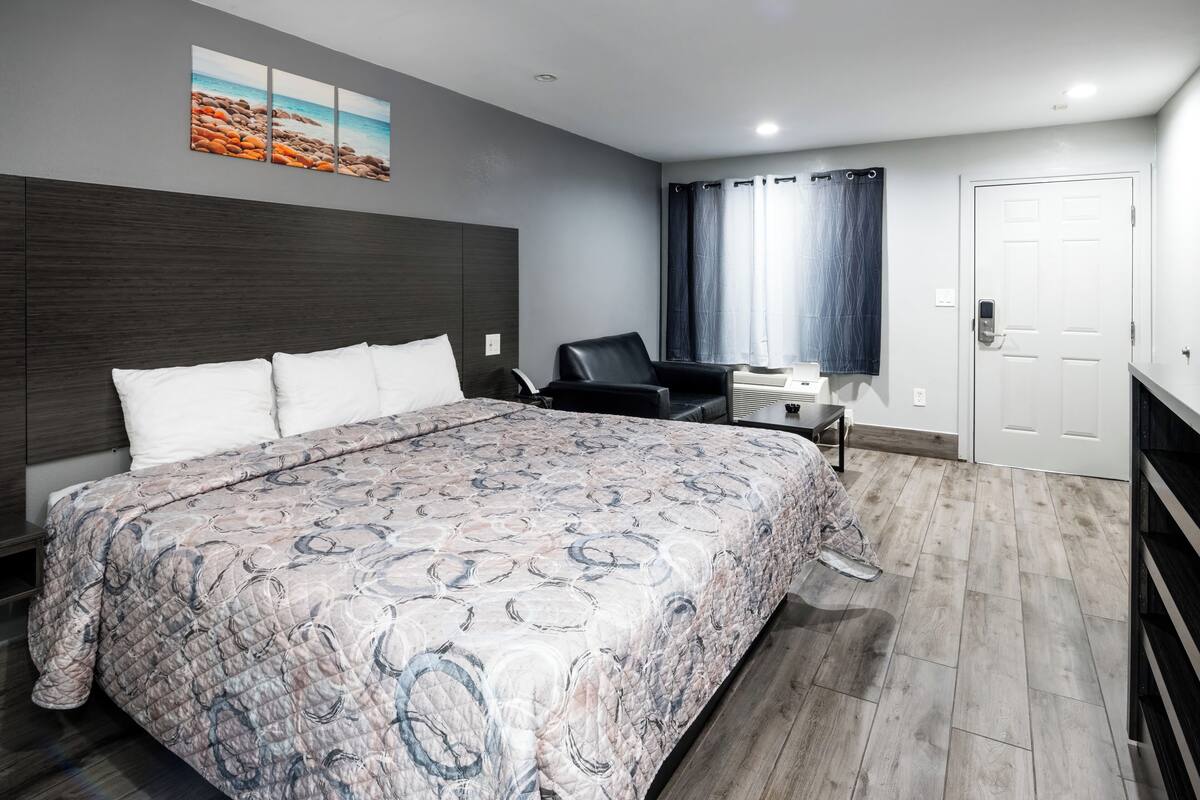 A modern hotel room with a large bed, a desk, and a chair.