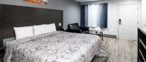 A modern hotel room with a large bed, a desk, and a chair.