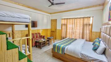 A room with bunk beds, a sofa, a chair, a small table, and a bed with a striped blanket.