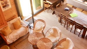 Una habitación acogedora con suelo de madera, un sofá, una mesa de comedor con sillas y un amplio ventanal.