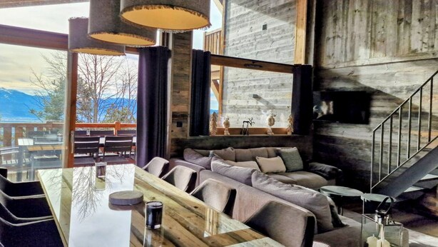A modern interior with a wooden wall, a sofa, a dining table, and a view of mountains. - Loft Odette (Font-Romeu-Odeillo-Via)