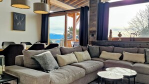 A modern living room with a large sectional sofa, a small round table, and a view of the outdoors. - Loft Odette (Font-Romeu-Odeillo-Via)