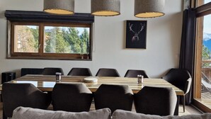 A dining area with a long table, six chairs, and three hanging lamps. - Loft Odette (Font-Romeu-Odeillo-Via)
