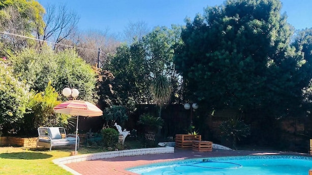 A backyard with a swimming pool, a brick patio, and a lawn.