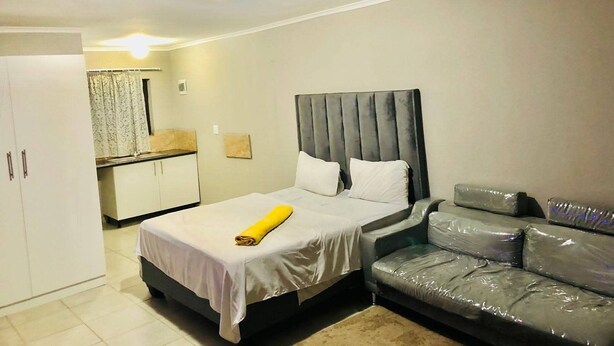 Une chambre à coucher avec un lit, un canapé, une armoire et une salle de bain visible au fond.