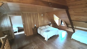A cozy attic bedroom with a wooden ceiling, a bed with striped bedding, a nightstand, and a window letting in natural light. - Fisherman's cottage Seasonal rental July (Piriac-sur-Mer)