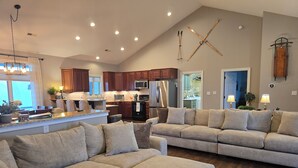 Uma sala de estar espaçosa com um amplo sofá modular, uma cozinha com armários de madeira e um espaço para refeições.