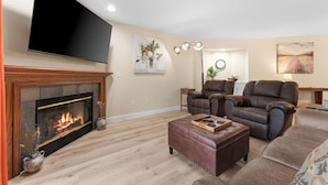 A living room with a fireplace, leather sofas, a flat-screen TV, and a painting on the wall. - Updated 2 bedroom walk-in with 2 king beds in Pointe Royale Golf Village (Branson)