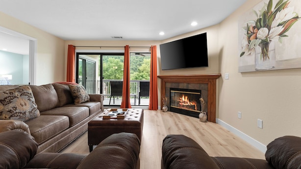 A living room with a leather sofa, a fireplace, and a flat-screen TV. - Updated 2 bedroom walk-in with 2 king beds in Pointe Royale Golf Village (Branson)
