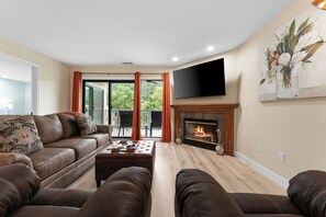 A living room with a leather sofa, a fireplace, and a flat-screen TV.