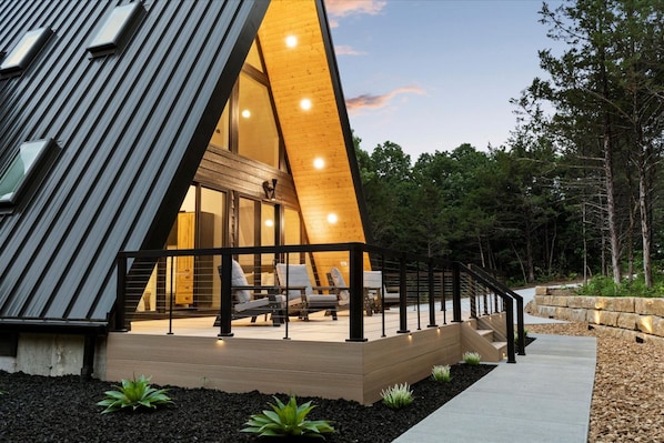 Un edificio moderno de forma triangular con fachada de madera y un área de balcón con asientos.