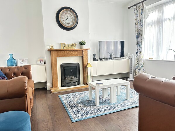 Una sala de estar con chimenea, televisor y sofá.