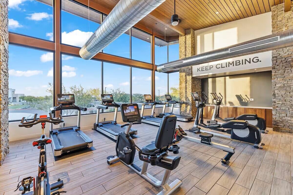 Une salle de sport équipée de tapis de course, de vélos d’appartement et d’appareils de musculation.