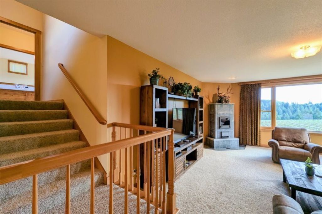 A staircase with wooden railings leading to a living area with a fireplace, a television, and a view of the outdoors.