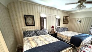 Un dormitorio con dos camas, ventilador de techo y alfombra estampada.