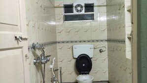 A small, narrow bathroom with a toilet, shower, and ventilation system.
