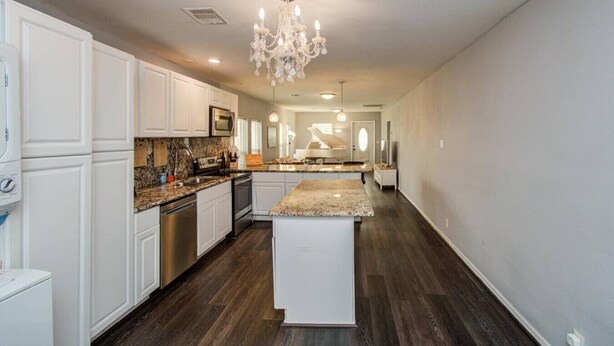 A spacious kitchen with white cabinetry, a granite countertop, and a central island.