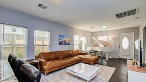 A spacious living room with a sectional sofa, a piano, and a television.