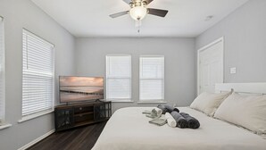 A bedroom with a bed, a TV, and a ceiling fan.