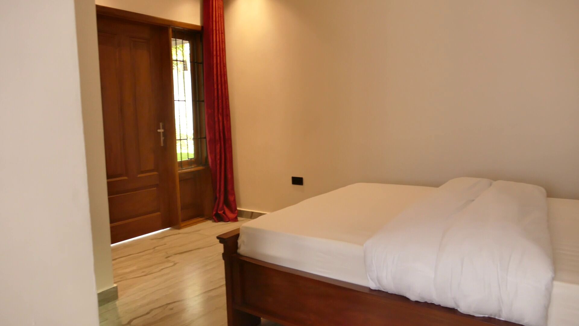 Un dormitorio con una cama de madera, una puerta y una ventana con cortina.