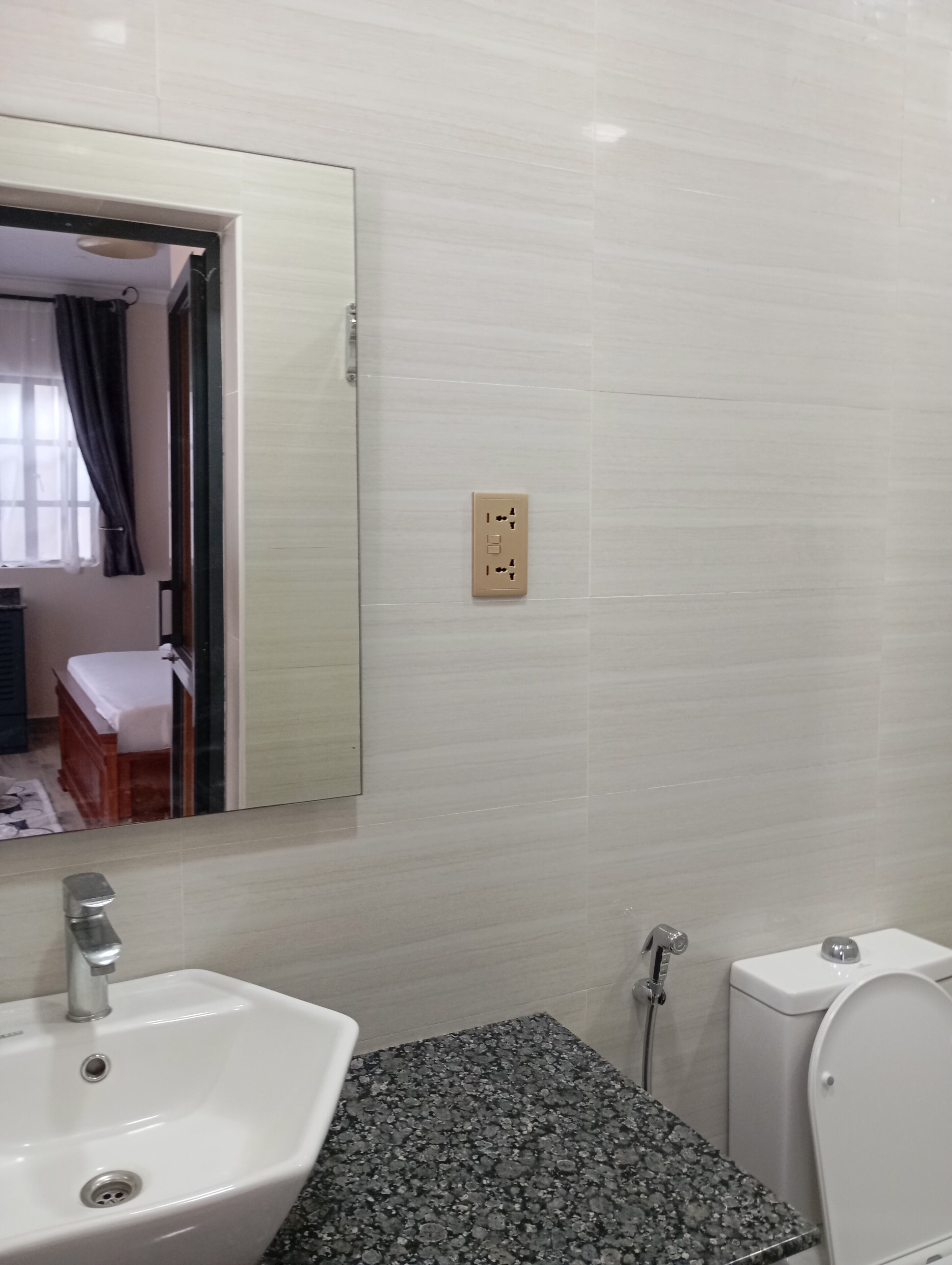 A bathroom with a white sink, a mirror, a toilet, and a shower.