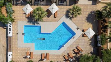 An aerial view of a swimming pool area with lounge chairs and umbrellas.