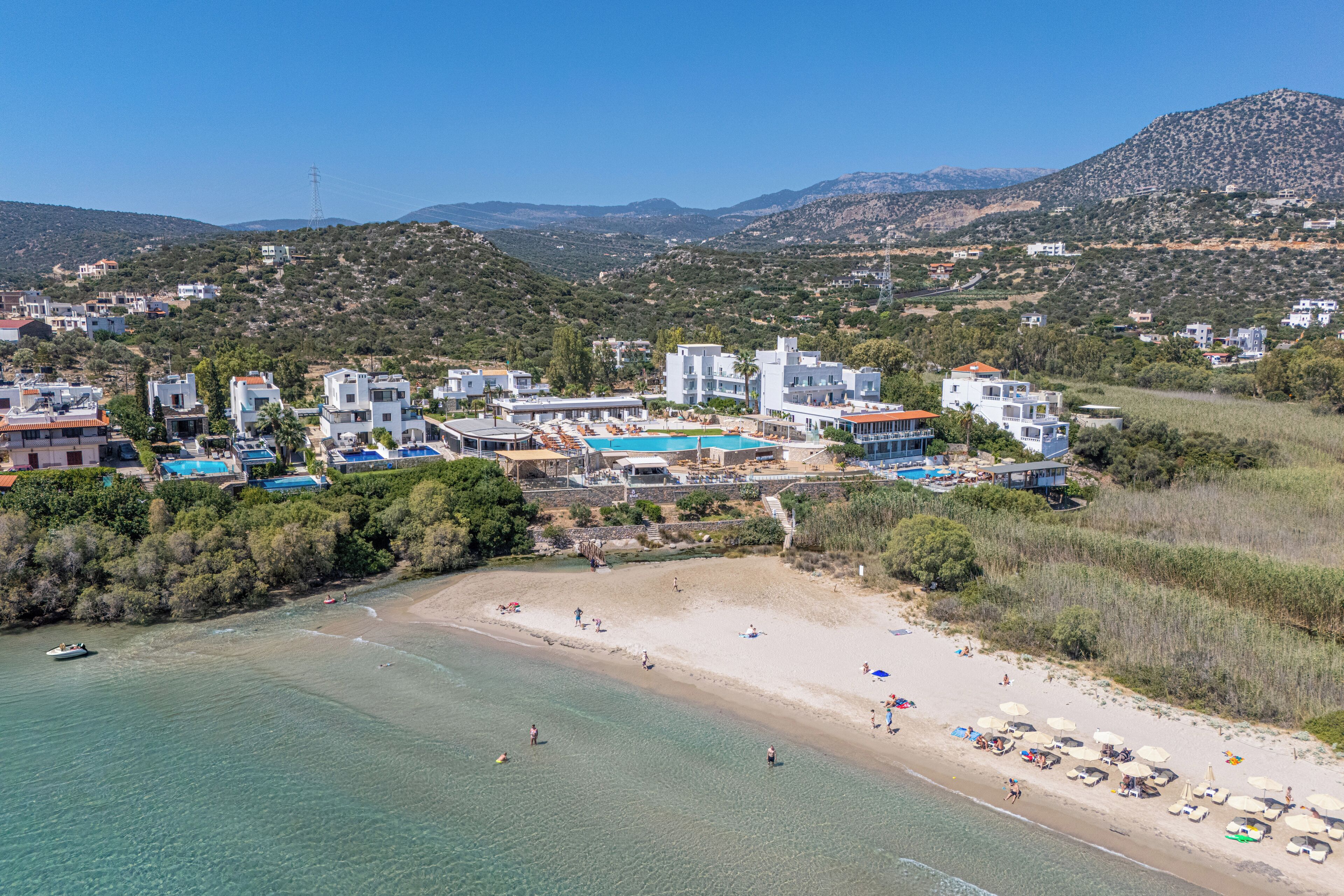 A coastal resort with a beach, clear waters, and modern buildings.