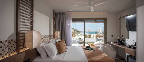 Una habitación de hotel con cama, mesita de noche, lámpara y vista a la playa.