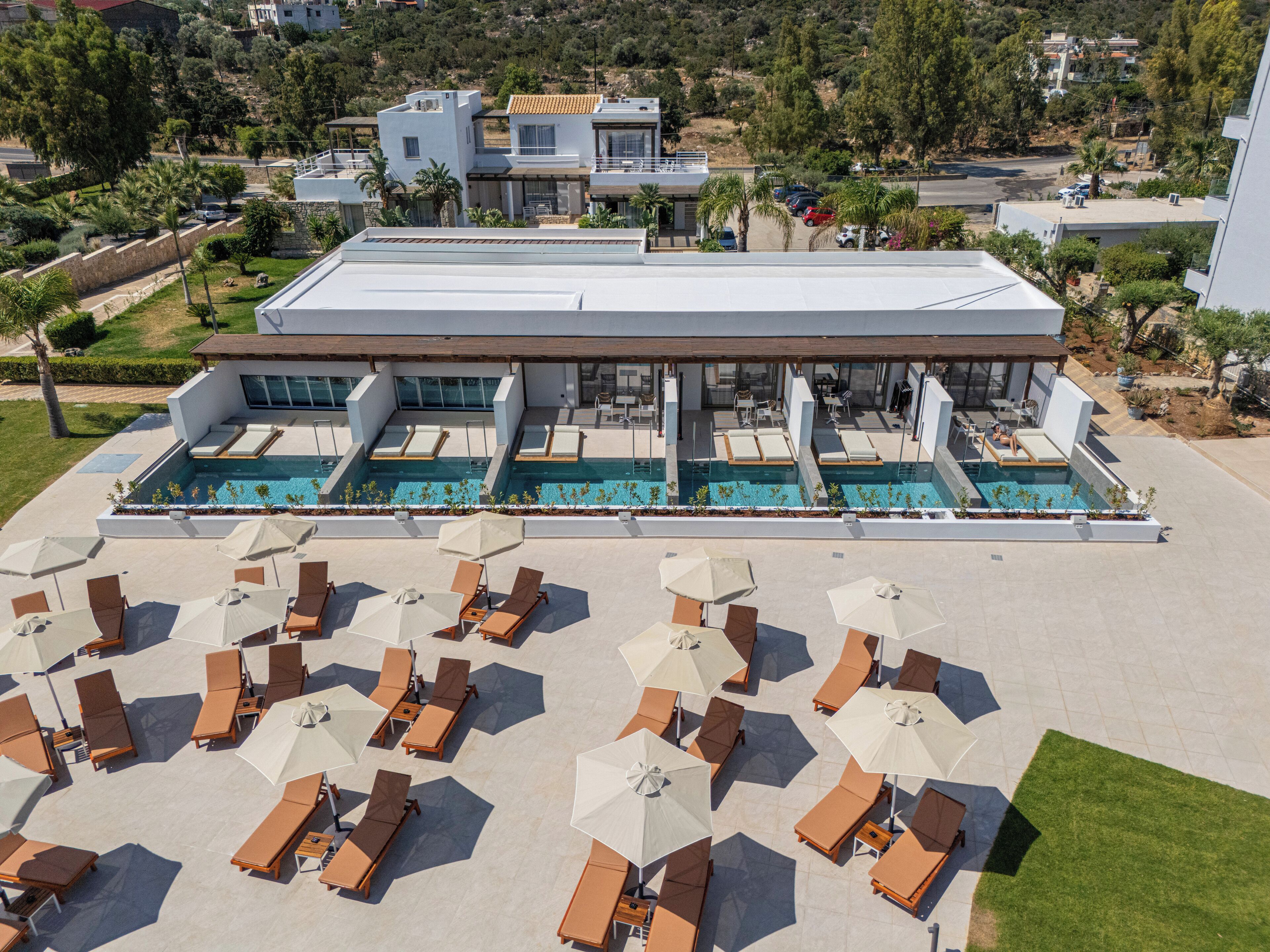 Um hotel moderno com área de piscina no terraço, várias piscinas e área de estar externa com guarda-sóis.