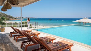 A poolside area with lounge chairs and a view of the sea. - The River Suites - Adults Only (Agios Nikolaos)
