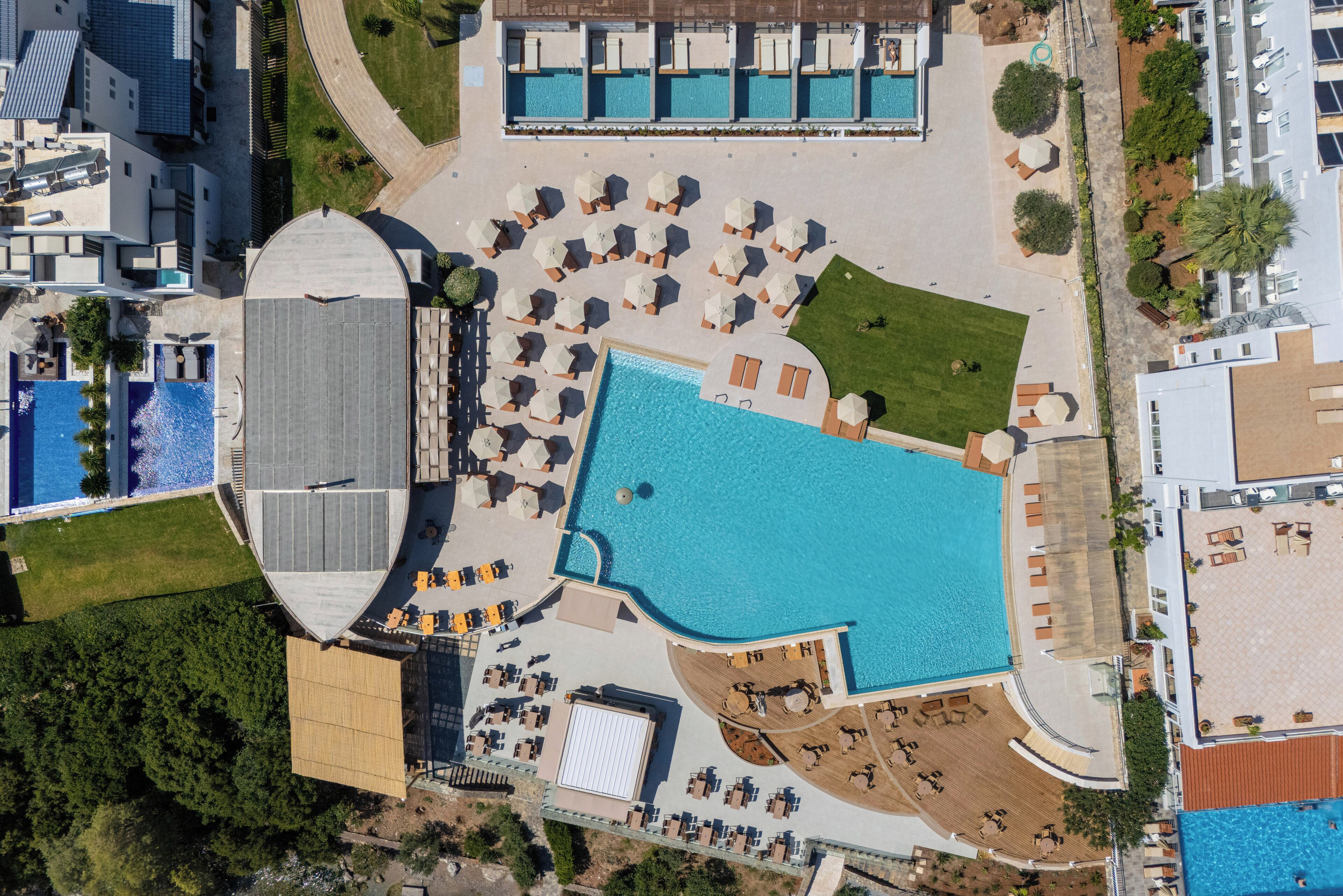 An aerial view of a resort with multiple swimming pools, sun loungers, and a large covered area.