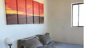A bedroom with a bed, a nightstand, a lamp, and a window. - Wild Goose Ranch (Homestead Valley)