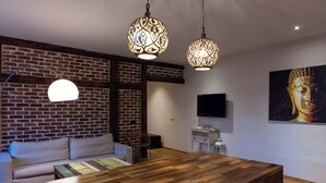 Una sala de estar moderna con una mesa de comedor de madera, una pared de ladrillo y un televisor montado.