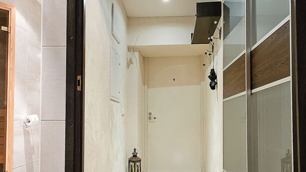 Un pasillo con suelo de madera, una puerta y una pared con marco negro.