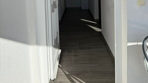 A hallway with a wooden floor and white walls.
